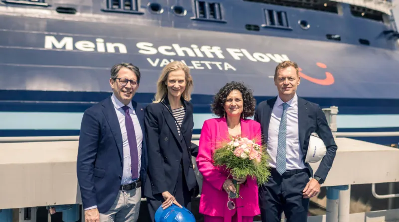 Vier Personen in festlicher Kleidung posieren vor dem Kreuzfahrtschiff "Mein Schiff Flow" in Valletta; eine Frau in Pink hält einen Blumenstrauß.