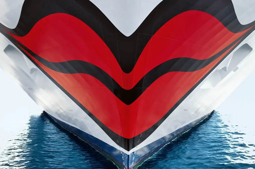 Bug eines AIDA-Kreuzfahrtschiffes mit dem markanten roten Kussmund-Design über der Wasserlinie.