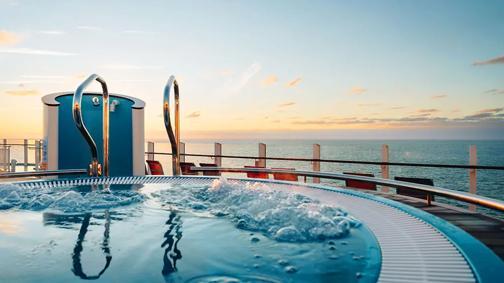 Ein Whirlpool an Deck eines Kreuzfahrtschiffes mit Blick auf das Meer bei Sonnenuntergang.