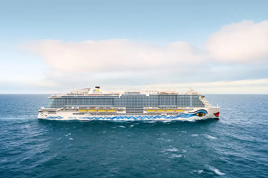 Das Kreuzfahrtschiff AIDAcosma fährt auf dem offenen Meer unter blauem Himmel.