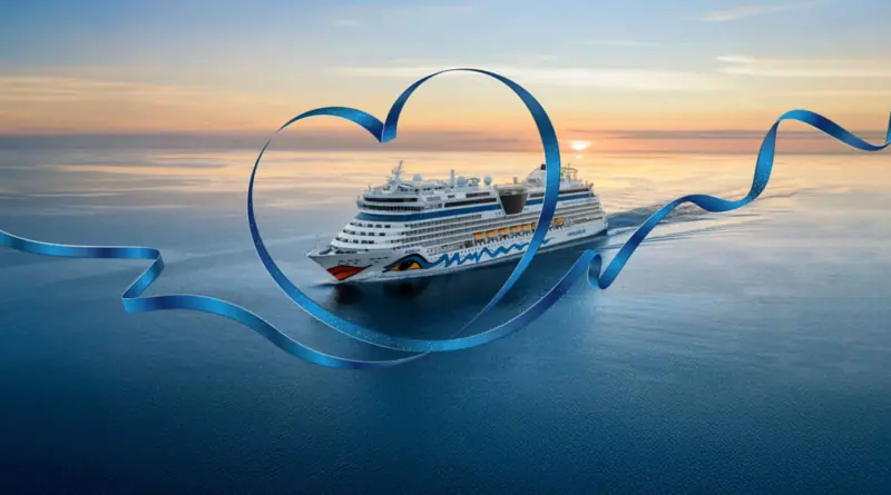 Kreuzfahrtschiff AIDAluna auf dem Meer bei Sonnenuntergang, eingerahmt von einem großen, blauen Herzband.