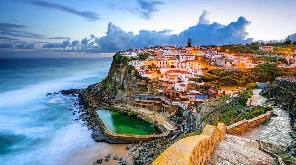 Küstenort Azenhas do Mar in Portugal, auf einem Felsen über dem Atlantik mit weißen Häusern und Naturpool am Meer.
