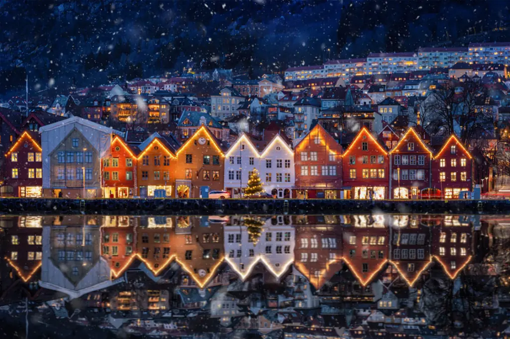 Weihnachtlich geschmückte Holzhäuser in Bergen, Norwegen, mit Lichterketten und Spiegelung im Wasser. Foto © SHansche / iStockphoto.