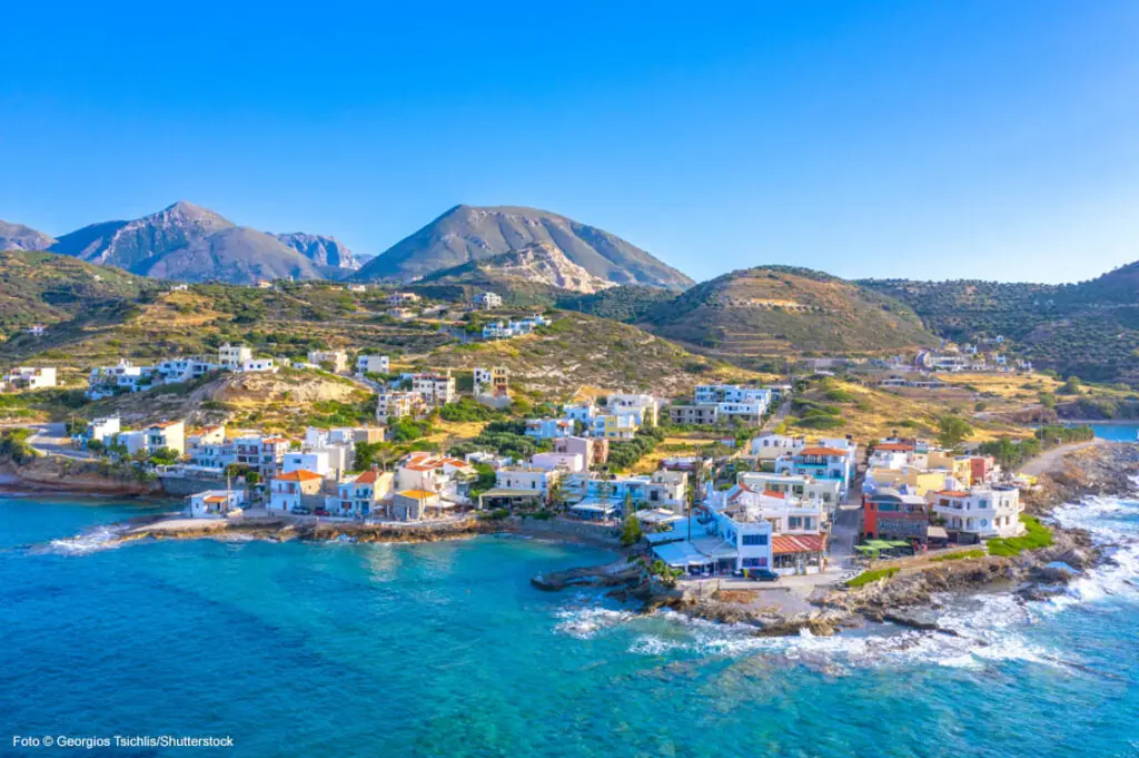 Küstenort auf Kreta mit traditionellen Häusern und Blick auf das Mittelmeer bei sonnigem Wetter.