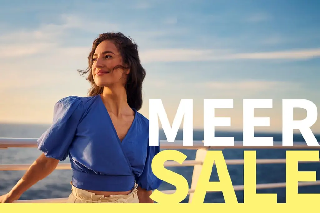 Frau an der Reling eines Mein Schiff Kreuzfahrtschiffes mit dem Schriftzug „MEER SALE“.