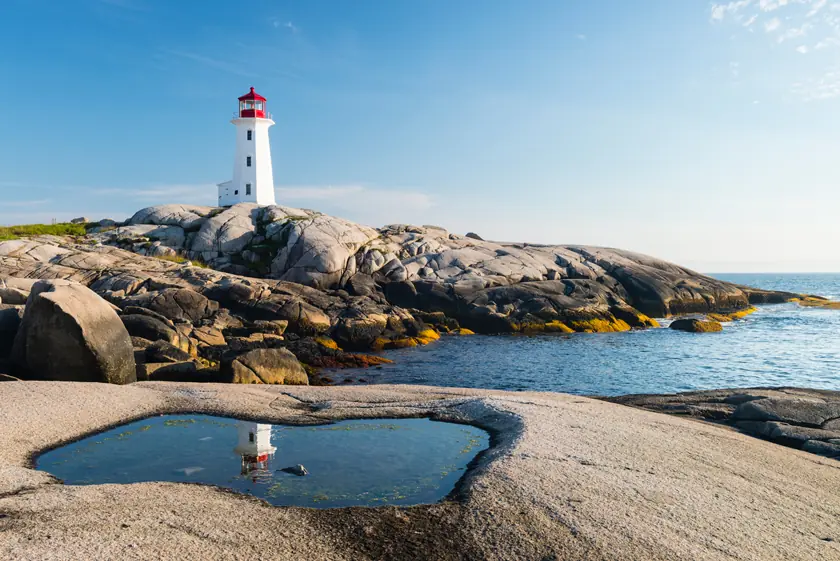 Weißer Leuchtturm von Peggy’s Cove mit roter Spitze auf Granitfelsen an der Atlantikküste von Nova Scotia in Kanada.